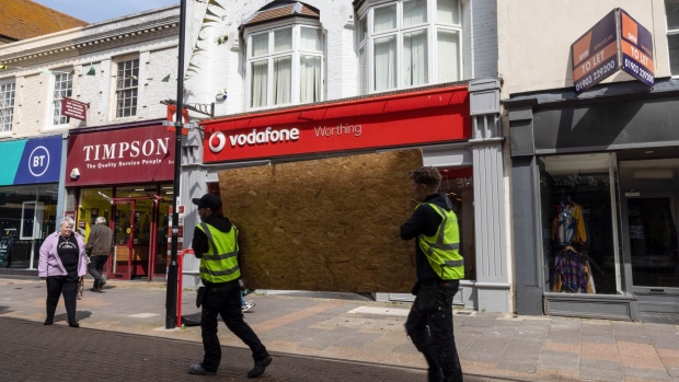 Workers carry wooden boards past a Vodafone Group Plc store in Worthing, UK, on Monday, May 15, 2023. Vodafone's full-year results, on Tuesday, May 16, give new chief executive officer Margherita Della Vallean opportunity to lay out her vision, which could entail cost cuts and a sustained dividend, Bloomberg Intelligencesaid.