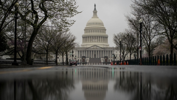 The U.S. Capitol is reflected in a pool of rain water on Capitol Hill in Washington, D.C., U.S., on Monday, March 23, 2020. U.S. senators in both political parties expressed confidence the Senate will approve a broad economic stimulus measure to address the coronavirus crisis later Monday, despite Sunday’s failed procedural vote on a Senate GOP measure that would have begun debate while talks on a bipartisan replacement bill continued.