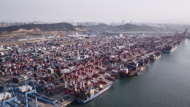 Cargo ships are moored under cranes as shipping containers stand at the Qingdao Qianwan Container Terminal in this aerial photograph taken in Qingdao, China, on Monday, May 7, 2018. China's overseas shipments exceeded estimates while imports surged, as the global economy continued to support demand. Photographer: Qilai Shen/Bloomberg