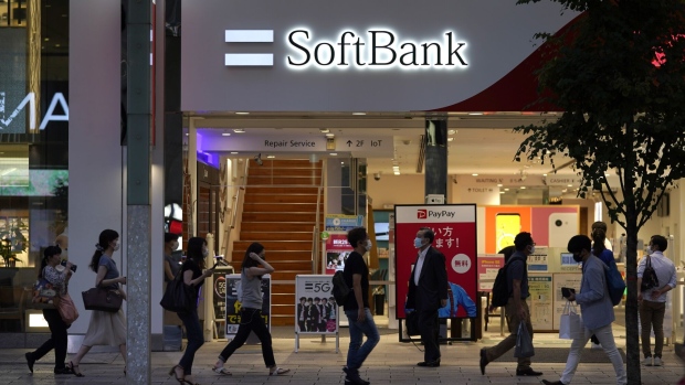 Pedestrians wearing protective masks walk past a SoftBank Corp. store in Tokyo, Japan, on Friday, Aug. 7, 2020. After reporting record losses in May and warning the coronavirus outbreak could be as devastating as the Great Depression, SoftBank Group founder Masayoshi Son is already poised to declare a recovery.