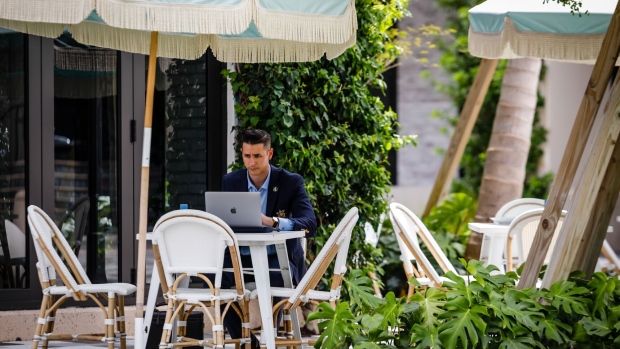 A customer works on a laptop computer in the outdoor dining area of Pura Vida restaurant on Rosemary Avenue in West Palm Beach, Florida, U.S., on Friday, Aug. 27, 2021. As Goldman Sachs and other big firms move in, developers plan a Manhattan-style makeover to Florida’s West Palm Beach.
