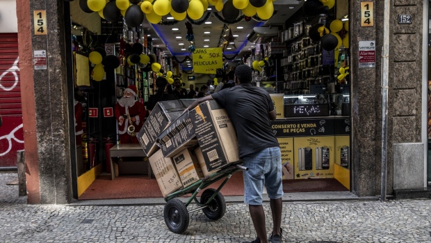 A worker holds a cart of products in front of a store on Black Friday in Rio de Janeiro, Brazil, on Friday, Nov. 25, 2022. Black Friday arrives as the traditional kickoff to Christmas shopping with year as a departure from 2021, when consumers splurged after pulling back during the pandemic.