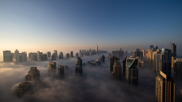 Morning fog shrouds residential and commercial skyscrapers in the Jumeirah Lakes Towers district of Dubai, United Arab Emirates, on Sunday, Jan. 17, 2021. Dubai is hoping one of the world’s fastest vaccination programs and rapid testing technology will help achieve its goal of holding the Expo 2020 event this year, after the coronavirus pandemic forced a delay. Photographer: Christopher Pike/Bloomberg