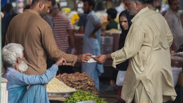 A vegetable vendor gives a change to a customer at a local market in Karachi, Pakistan, on Thursday, June 30, 2022. Pakistani government has increased gasoline prices by 14.83 rupees/liter to 248.74 rupees/liter effective July 1, the Pakistan Finance Ministery said in a statement. The levy imposed as one of prior actions set by the International Monetary Fund to to revive its loan program, Pakistan Finance Minister Miftah Ismail says at news conference. IMF to extend its bailout program to four years and enhance its funding by $1b to $7b. Photographer: Asim Hafeez/Bloomberg
