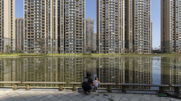 A woman and child stop by a canal in front of apartment buildings at China Evergrande Group's Life in Venice real estate and tourism development in Qidong, Jiangsu province, China, on Tuesday, Sept. 21, 2021. Evergrande slid deeper in equity and credit markets Tuesday, fueling concerns about broader contagion after S&P Global Ratings said the developer is on the brink of default.