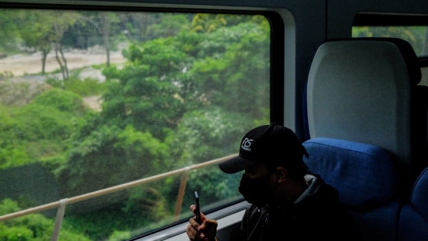 A passenger uses a smartphone to take a photograph from inside an ERL train during an event to mark a special RM1 Joyride fare on Express Rail Link Sdn Bhd (ERL) services in Kuala Lumpur, Malaysia, on Saturday, Nov. 27, 2021. The 2-day event aims to stimulate local leisure travel and rebuild the public's confidence in using public transportation, while promoting the new KLIA Ekspres mobile application. Photographer: Samsul Said/Bloomberg