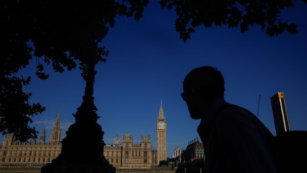 A commuter passes the Houses of Parliament in London, UK, on Monday, July 11, 2022. UK Prime Minister Boris Johnson quit as Conservative leader last Thursday after a dramatic mass revolt from his ministers, following a series of scandals that have overshadowed his three-year premiership. Photographer: Jason Alden/Bloomberg
