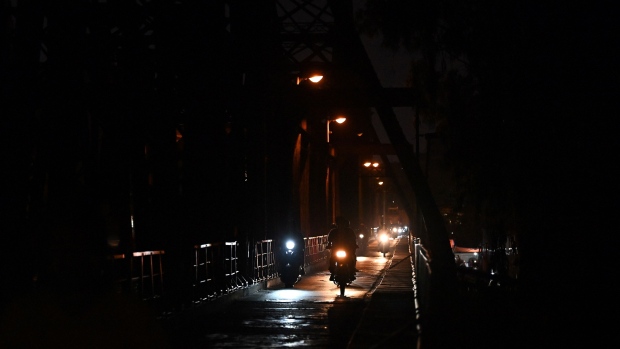 This photo taken on May 30, 2023 shows motorbike riding on Long Bien bridge in Hanoi as some street lights were turned off to save electricity. Photographer: Nhac Nguyen/AFP/Getty Images