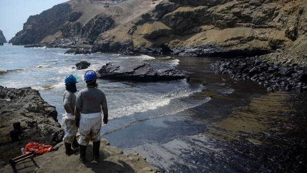 Workers observe an oil spill on Cavero beach in Callao, Peru, on Wednesday, Jan. 19, 2022. High ocean waves stemming from a massive volcanic eruption near Tonga caused an oil spill off the coast of Peru, closing beaches and halting fishing after the country's Navy failed to issue a tsunami warning.