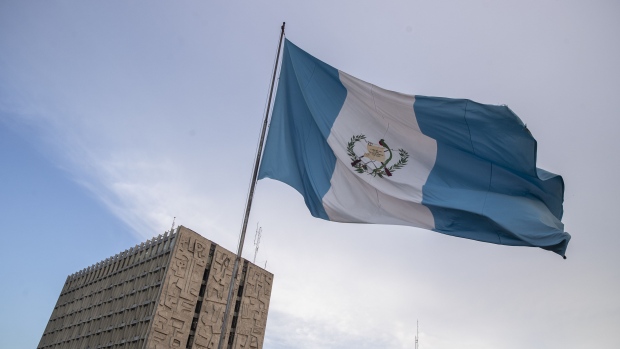 A Guatemalan flag stands in front of the Bank of Guatemala in Guatemala City, Guatemala, on Friday, Dec. 13, 2019. U.S. President Donald Trump met with Guatemalan President Jimmy Morales last week, where the two discussed a July agreement to stem the flow of Central American migrants coming to the U.S.-Mexico border. Photographer: Victor J. Blue/Bloomberg