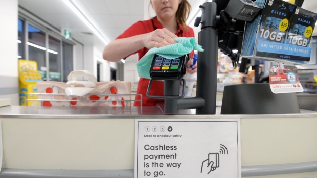 An employee wipes down a card payment pad at a checkout of a Coles Supermarket, operated by Coles Supermarkets Australia Pty, in the Collingwood neighborhood of Melbourne, Australia, on Thursday, April 2, 2020. Australian shares slid as worries over the economic effects of the coronavirus outbreak intensified. Photographer: Carla Gottgens/Bloomberg