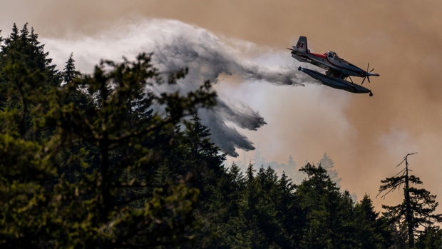A fixed wing waterbomber drops water onto the Cameron Bluffs wildfire near Port Alberni, British Columbia, Canada, on Tuesday, June 6, 2023. Canada is on track to see its worst-ever wildfire season in recorded history if the rate of land burned continues at the same pace. Photographer: James MacDonald/Bloomberg
