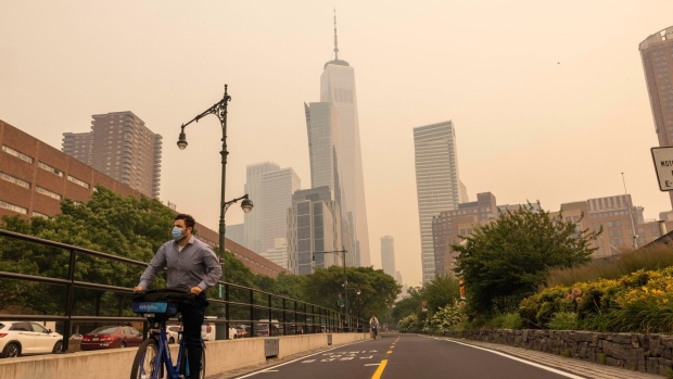 A cyclist wears a mask as smoke from Canada wildfires blankets New York, US, on Wednesday, June 7, 2023. The US Northeast, including New York City, will continue to breathe in choking smoke from fires across eastern Canada for the next few days, raising health alarms across impacted areas. Photographer: Alex Kent/Bloomberg