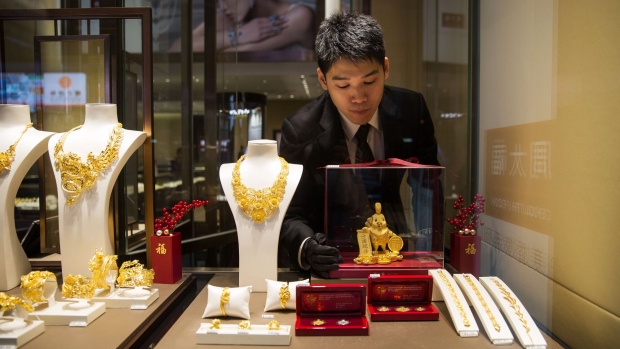 An employee arranges gold rooster figurines in the window of a Chow Tai Fook Jewellery Group Ltd. store in the Central district of Hong Kong, China, on Friday, Jan. 20, 2017. Chow Tai Fook, the world's largest jewelry chain, last year launched the first of a line of mainland shops selling lower-priced jewelry, with average prices of 2,000 yuan ($291), about a third the prices at its flagship stores.