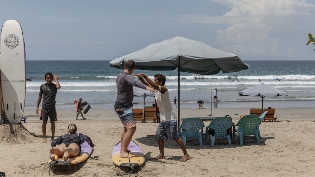 Visitors take a surfing lesson on a beach in Kuta. Photographer: Nyimas Laula/Bloomberg