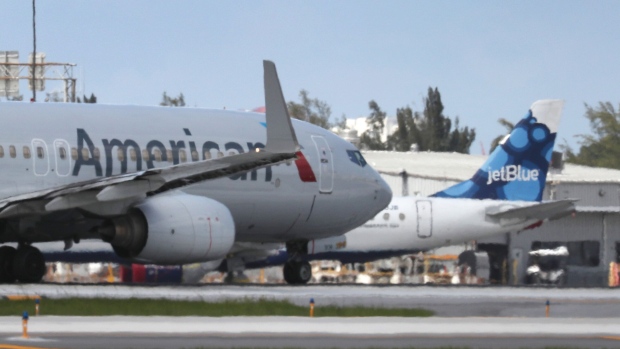 FORT LAUDERDALE, FLORIDA - JULY 16: An American Airlines plane takes off near a parked JetBlue plane at the Fort Lauderdale-Hollywood International Airport on July 16, 2020 in Fort Lauderdale, Florida. JetBlue Airways and American Airlines Group announced they will be creating an alliance between the two companies. (Photo by Joe Raedle/Getty Images)