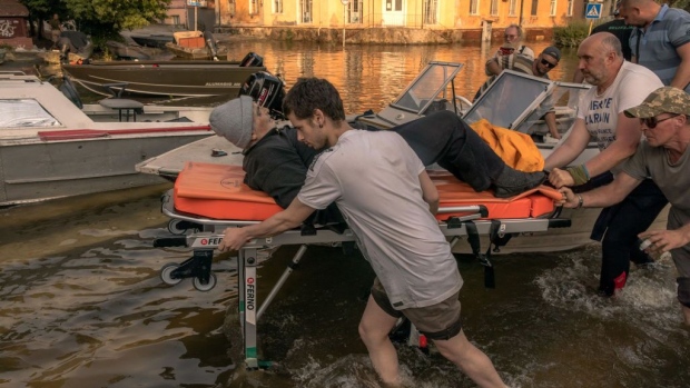 KHERSON, UKRAINE - JUNE 09: Volunteers and others push a stretcher carrying an elderly person who was evacuated from a flooded area on June 9, 2023 in Kherson, Ukraine. Early Tuesday, the Kakhovka dam and hydroelectric power plant, which sit on the Dnipro river in the southern Kherson region, were destroyed, forcing downstream communities to evacuate due to the risk of flooding. The cause of the dam's collapse is not yet confirmed, with Russia and Ukraine accusing each other of its destruction. The Dnipro river has served as a frontline between the warring armies following Russia's retreat from Kherson and surrounding areas last autumn. The dam and plant had been under the control of Russia, which occupies a swath of land south and southeast of the river. (Photo by Roman Pilipey/Getty Images)