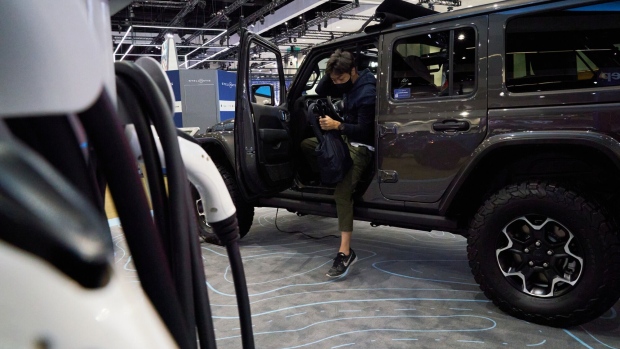 An attendee exits a 2021 Jeep Wrangler 4xe plug-in electric hybrid sports utility vehicle (SUV) on display at AutoMobility LA ahead of the Los Angeles Auto Show in Los Angeles, California, U.S., on Thursday, Nov. 18, 2021. Covid-19 canceled the Los Angeles Auto Show in 2020 and now that the show is back, some automakers have decided they didn't need it anyway.