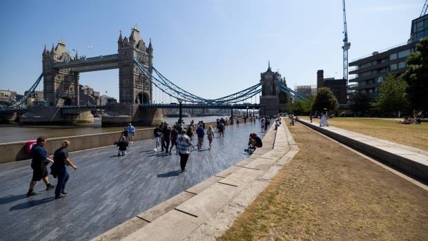 Visitors pass pass along the embankment near Tower Bridge in London, UK, on Saturday, June 10, 2023. Soaring temperatures caused by a blast of hot air led the UK to post fresh health warnings through the weekend. Photographer: Chris Ratcliffe/Bloomberg