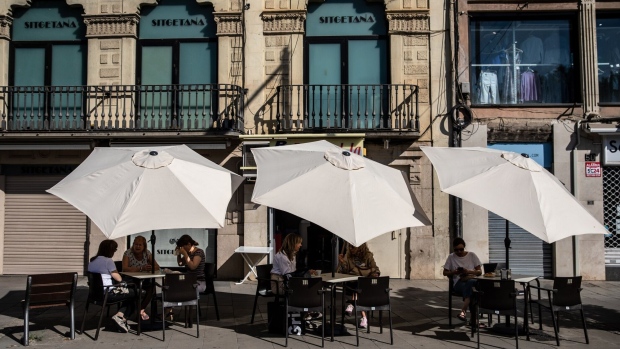 Customers shelter from the sun under parasols at a cafe terrace area in Lleida, Spain, on Wednesday, June 1, 2022. Temperatures in Spain will reach unusually high levels for this time of the year amid a heat wave that’s expected to take thermometers above 40 degrees Celsius (104 Fahrenheit) in some parts of the country.