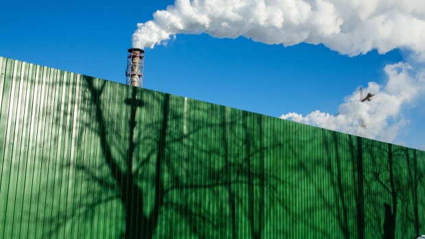 Green fence in front of chimneys. Photographer: Andrey Rudakov/Bloomberg