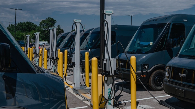 Amazon.com delivery electric vans (EV), built by Rivian Automotive, at charging stations parked outside the Amazon Logistics warehouse in Chicago, Illinois, US, on Thursday, July 21, 2022. Amazon.com Inc. is starting delivery of packages to US customers using the first of as many as 100,000 electric vans built by Rivian Automotive Inc., which aims to hand over thousands of the vehicles this year.
