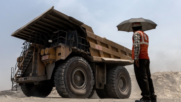 A mining worker under an umbrella shelters from the sun as a dump truck passes at the coal mine, operated by South Eastern Coalfields Ltd., in Gevra, Chhattisgarh, India, on Wednesday, May 10, 2023. India has to keep its power grid standing to cope with brutal temperatures, digging up expanding quantities of the dirtiest fossil fuel. Photographer: Anindito Mukherjee/Bloomberg