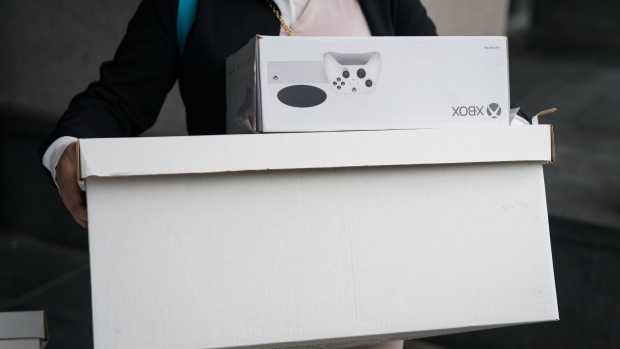 A legal team member carries materials including carrying an XBox Series S video game console while arriving to court in San Francisco, California, US, on Friday, June 23, 2023. Microsoft and Activision Blizzard CEOs are expected to testify to persuade a federal judge in California to reject the Federal Trade Commissions effort to block their $69 billion deal.