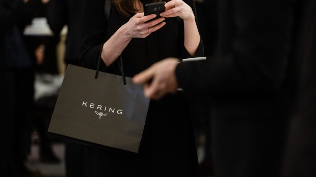 An attendee uses a smartphone while holding a Kering SA branded gift bag ahead of a news conference to announce the company's full year earnings in Paris, France, on Tuesday, Feb. 12, 2019. Kering’s Gucci label outpaced competitors in the fourth quarter, though the 28 percent sales growth won little applause from investors who had high expectations after rival LVMH trounced estimates last month. Photographer: Marlene Awaad/Bloomberg