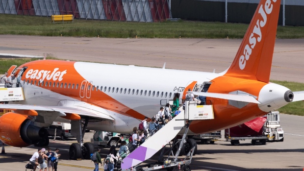 Passengers board an aircraft, operated by EasyJet Plc, at London Luton Airport in Luton, UK, on Friday, May 26, 2023. Ticket prices across the industry have been edging higher, partly because of robust demand for summer getaways, and partly because of a scarcity of aircraft as airlines clamor to get hold of new models. Photographer: Chris Ratcliffe/Bloomberg