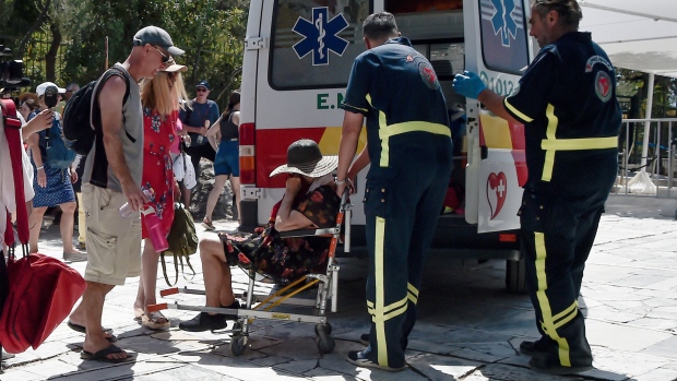 Medics help a woman who has passed out from the heat during a heat wave in Athens, Greece, on July 20.
