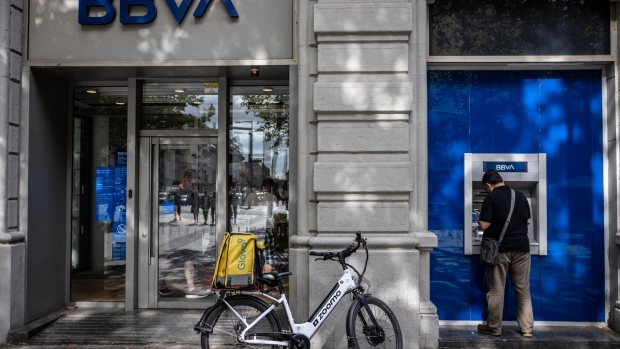 A Glovo cycle courier uses an automated teller machine (ATM) outside a Banco Bilbao Vizcaya Argentaria SA (BBVA) bank branch in Barcelona, Spain, on Wednesday, July 26, 2023. BBVA reports earnings on July 28. Photographer: Angel Garcia/Bloomberg