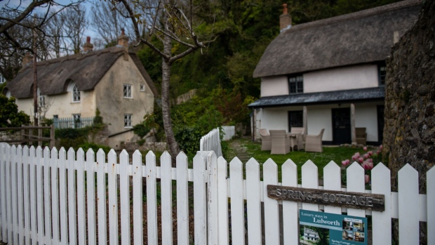 A holiday rental cottage sits unoccupied beyond a white picket fence during the national lockdown on Easter weekend in Lulworth Cove, U.K., on Friday, April 10, 2020. The U.K. will tighten a nationwide lockdown if needed to halt the spread of coronavirus, Health Secretary Matt Hancock said, as officials face demands to say how they will eventually lift the restrictions that have brought normal life to a standstill.