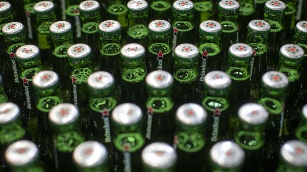 Lids sit on green Heineken beer bottles moving along a conveyor at the Heineken NV brewery in Zoeterwoude, Netherlands, on Wednesday, May 30, 2018. Heineken has acquired Stellenbrau, a beer maker based in South Africa's western Cape, submitted a bid for a local Coca-Cola bottler and built a brewery in Ivory Coast to take on market leader Castel. Photographer: Jasper Juinen/Bloomberg