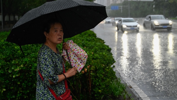 A woman shelters from the rain with an umbrella in Beijing on July 31. Photographer: Pedro Pardo/AFP/Getty Images