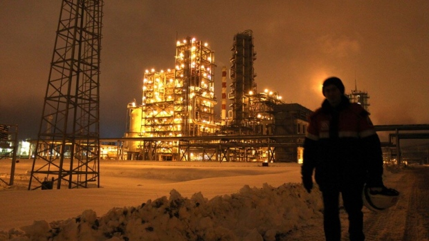 An employee carries a safety helmet through the snow at the illuminated Lukoil-Nizhegorodnefteorgsintez petroleum refinery, operated by OAO Lukoil, in Nizhny Novgorod, Russia.