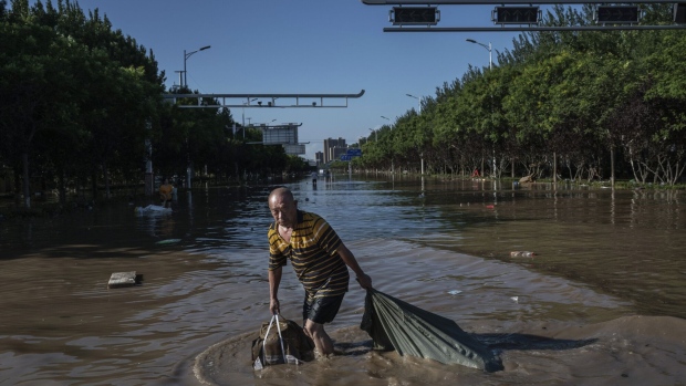 A man wades through receding floodwaters in Zhuozhou, Hebei Province on Aug. 5. Photographer: Kevin Frayer/Getty Images