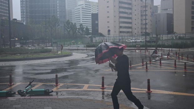 A man uses his umbrella in the southeastern port city of Busan, as Typhoon Khanun approaches, on Aug. 10. Photographer: Anthony Wallace/AFP/Getty Images