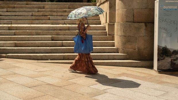 A shopper uses an umbrella as protection from the sun during a heatwave in Ourense, Spain, on Tuesday, Aug. 8, 2023. Heatwaves may “reduce Southern Europe’s attractiveness as a tourist destination in the longer term or at the very least reduce demand in summer,” according to Moody’s Investors Service.
