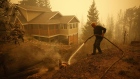 A resident sprays water on hot spots near a house in Celista, British Columbia on Aug. 19. Record-breaking wildfires in Canada have already scorched an area larger than Greece this year. Photographer: Cole Burston/Bloomberg