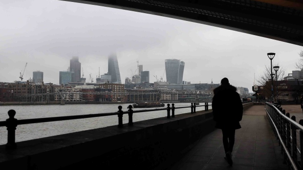 A pedestrian passes beneath Blackfriars bridge against a backdrop of sky scrapers surrounded by fog in the City of London, U.K., on Wednesday, Feb. 8, 2017. London's poor air quality set a modern record at the end of January, during a spate of pollution that occurred when cold, windless weather trapped emissions over the capital. Photographer: Chris Ratcliffe/Bloomberg