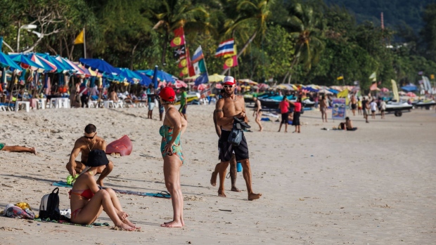 Visitors sit and walk along Patong Beach in Phuket, Thailand, on Thursday, July 6, 2023. Russian nationals were the No. 1 source of tourists to the island this year, according to the Phuket Tourist Association. Photographer: Andre Malerba/Bloomberg