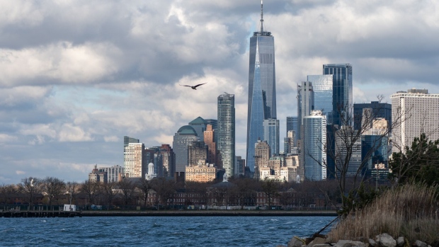 A bird flies near Governors Island and the Manhattan skyline in the Red Hook neighborhood of the Brooklyn borough of New York, U.S., on Tuesday, Dec 1, 2020. Red Hook, a sleepy neighborhood on Brooklyn's waterfront, has become a magnet for e-commerce distribution centers over the past few years, thanks to its cheaper real estate and easy highway access. Photographer: Jeenah Moon/Bloomberg