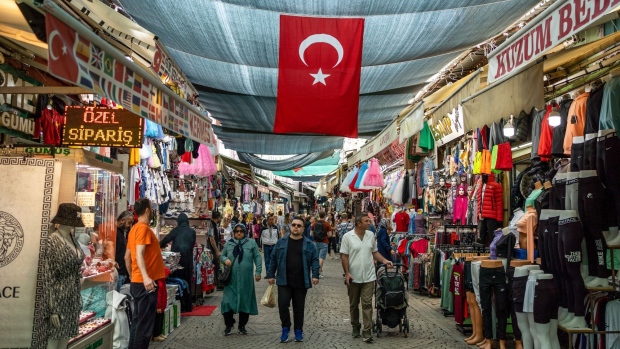 A Turkish national flag hangs above stores at a local bazaar in Izmir, Turkey, on Friday, May 19, 2023. Turkey’s lira is heading for its worst week since July as the country prepares for a runoff presidential vote in 10 days, as the cost of insuring government bonds against default increases further.
