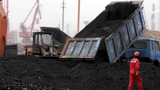 A worker walks past a truck unloading coal at a loading dock in Shanghai, China. Photographer: Qilai Shen/Bloomberg 