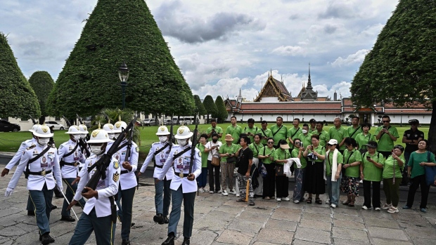 Chinese tourists watch a changing of the guards at the Grand Palace in Bangkok. Photographer: Lillian Suwanrumphal/AFP/Getty Images