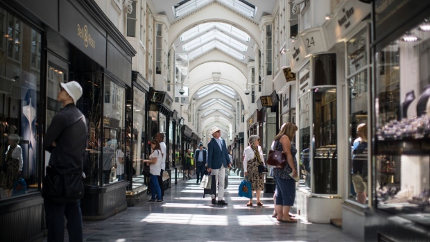 Shoppers browse the window displays of luxury goods stores as they walk through Burlington Arcade in central London, U.K., on Friday, Jun. 29, 2018. Nevermind West End shopfronts and Mayfair offices, the big money in London real estate is chasing small warehouses.