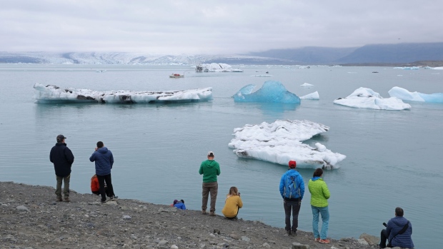 HOF, ICELAND - AUGUST 15: Tourists look at icebergs that have broken off of receding Breidamerkurjokull glacier, which looms behind, at Jokulsarlon lake on August 15, 2021 near Hof, Iceland. Breidamerkurjokull, among the biggest of the dozens of glaciers that descend from Vatnajokull ice cap, is melting, losing an average of 100 to 300 meters in length annually. Breidamerkurjokull's meltwater has created Jokulsarlon, which is now Iceland's biggest lake. Iceland is undergoing a strong impact from global warming. Since the 1990s, 90 percent of Iceland's glaciers have been retreating and projections for the future show a continued and strong reduction in size of its five ice caps. (Photo by Sean Gallup/Getty Images)
