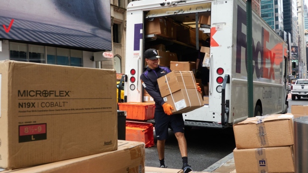 Workers for an independent contractor to FedEx Corp. unload packages from a delivery truck in New York, US, on Monday, June 26, 2023. FedEx Corp. said it cut 29,000 US jobs over the past year and issued a 2024 profit outlook that missed Wall Street's expectations as it continues to trim costs in the face of waning package delivery demand.
