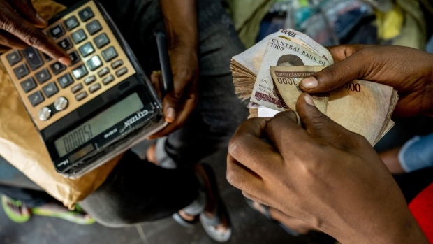 A customer counts out payment from a bundle of Naira banknotes inside a market in Lagos, Nigeria, on Friday, April 22, 2022. Choked supply chains, partly due to Russia’s invasion of Ukraine, and an almost 100% increase in gasoline prices this year, are placing upward price pressures on Africa’s largest economy. Photographer: Damilola Onafuwa/Bloomberg